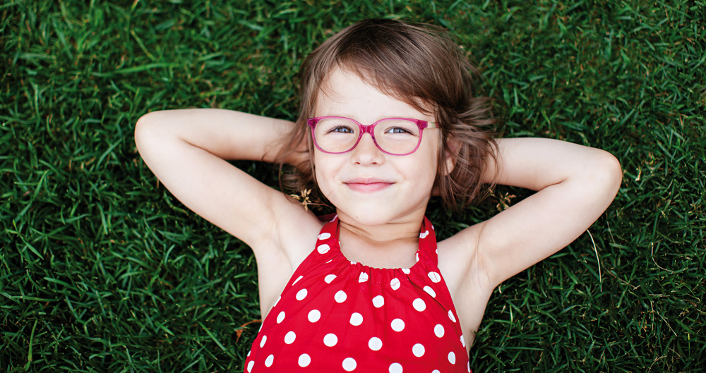 Niña con gafas sonriendo porrque cuidan de su salud visual