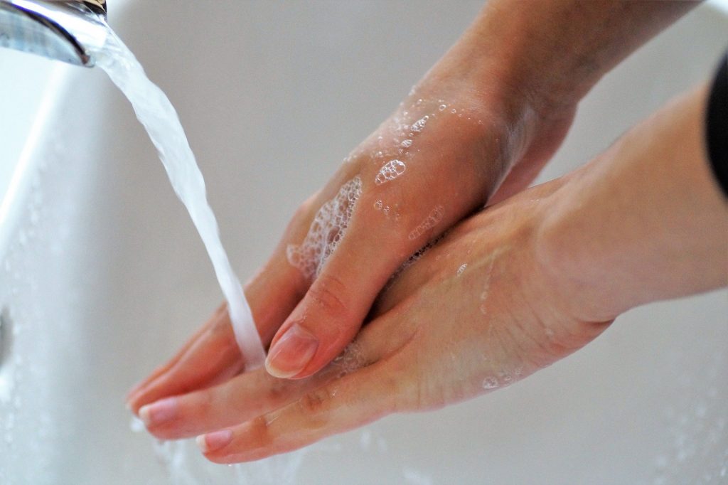 Una persona se lava las manos con agua y jabón antes de desinfectar gafas 